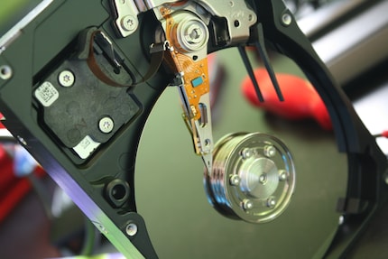 Eine Festplatte gleicht visuell einem Schallplattenspieler mit einem Lese/Schreibarm und einer Platte.